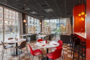restauracja z białymi stołami i czerwonymi krzesłami w obiekcie Ibis Praha Mala Strana w Pradze