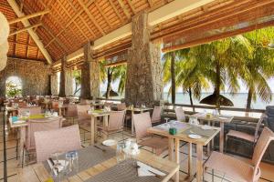 ein Restaurant am Strand mit Tischen und Stühlen in der Unterkunft Cocotiers Hotel – Mauritius in Port Louis