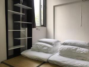 2 camas blancas en una habitación con estantería en Dan Hostel丹居青旅 en Taipéi