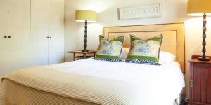 1 dormitorio con 1 cama blanca y 2 almohadas en Navarre Farm Cottages en Stellenbosch