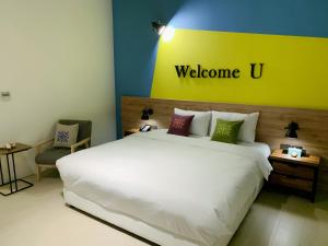 a bedroom with a white bed with a welcome sign on the wall at Tian Zhong Hotel in Tianzhong