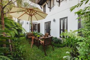 - une table et des chaises avec un parasol dans la cour dans l'établissement El Barrio Lanna- SHA Extra Plus, à Chiang Mai