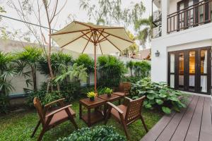 patio con tavolo, sedie e ombrellone di El Barrio Lanna- SHA Extra Plus a Chiang Mai