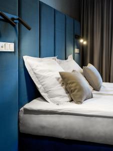 a bed with white pillows and a blue wall at Hotel Logos Kraków in Krakow