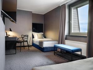 a hotel room with a bed and a desk and a window at Hotel Logos Kraków in Krakow