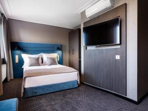a bedroom with a bed and a flat screen tv at Hotel Logos Kraków in Krakow