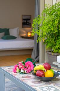a table with a plate of fruit and flowers on it at Hidesign Athens Luxury Apartments in Kolonaki in Athens