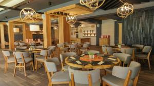 un restaurante con mesas de madera, sillas y lámparas de araña en DIT Evrika Beach Club Hotel - All Inclusive en Sunny Beach