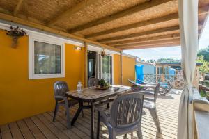 a patio with a wooden table and chairs on a deck at Camping Adria Mobile Homes Lanterna in Poreč