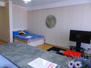 uma pequena sala de estar com um sofá e uma televisão em Panoramic studio apartments with mountain views em Bishkek