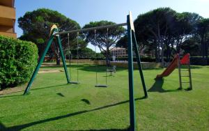 a park with three swings in the grass at Apartaments Beach & Golf Resort in Pals