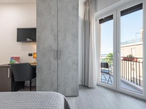 a bedroom with a bed and a desk and a balcony at Diaz Apartment in Cagliari