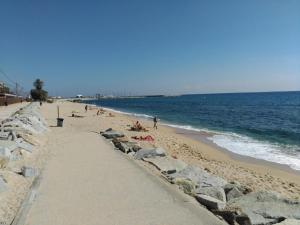 a beach with people laying on the sand and the water at Apartament Can Batlle in Premiá de Mar