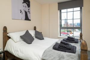 a bedroom with a white bed with towels on it at Stylish & Cosy Apartment in Nottingham