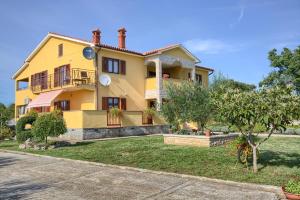 una casa amarilla con un patio delante en Appartman Rozana en Barban