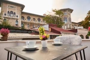 una mesa con 2 tazas y flores en el balcón en Seven Rooms Oldcity Hotel, en Estambul