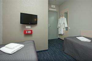 um quarto com uma cama e uma televisão e um vestido pendurado numa parede em Air Express INSIDE Sheremetyevo FREE ZONE em Khimki