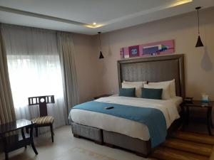 a bedroom with a large bed with a blue blanket at Ace Premier Hotel in Abuja