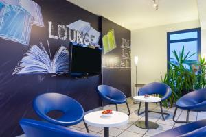a waiting room with blue chairs and a flat screen tv at ibis budget Chilly-Mazarin Les Champarts in Chilly-Mazarin