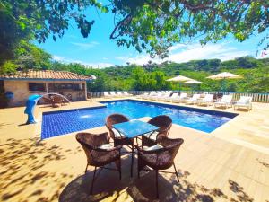 un patio con mesa y sillas junto a una piscina en Hotel Miratlantico Búzios, en Búzios