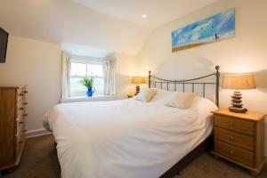 纽基Bejowan Cornish Cottage的卧室里有一张白色的大床和一扇窗户