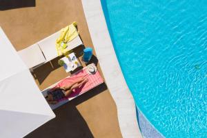an overhead view of a swimming pool with a woman in a bikini next to it at Mandraki Village Boutique Hotel in Koukounaries
