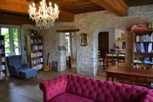 sala de estar con sofá púrpura y comedor en Le Figuier, Large house with pool, gym & separate gite, en Saint-Ythaire