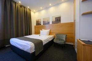 ein Hotelzimmer mit einem Bett und einem Stuhl in der Unterkunft Hotel Heymann in Kaiserslautern