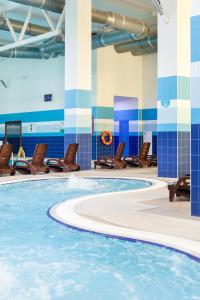 una piscina en un edificio con sillas marrones en AMAKS Krasnaya Pakhra Resort, en Krasnoye