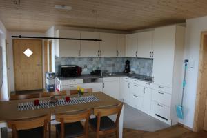 a kitchen with white cabinets and a table with chairs at Schwarzwaldhuus Feldberg in Feldberg +5 photos
