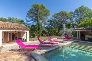 un grupo de sillas rosas sentadas junto a una piscina en Villa les Pins, en Callas