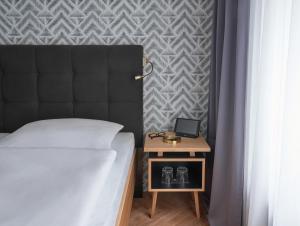 a bedroom with a bed and a nightstand with a table at Hotel MIO by AMANO in Munich
