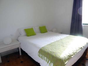 a white bed with two green pillows on it at Costa Antigua in Costa de Antigua