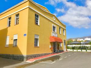 a yellow building with a red awning next to a street at Hotel Pensión Cassandra in Buzanada