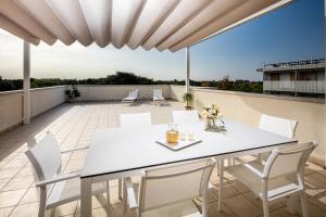 eine Terrasse mit einem weißen Tisch und Stühlen auf dem Dach in der Unterkunft Residence AIRONE in Lignano Sabbiadoro