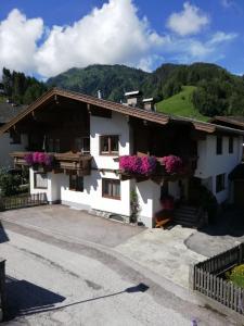 ein weißes Gebäude mit Blumen an den Fenstern in der Unterkunft Ferienwohnung Innerhofer in Hollersbach im Pinzgau