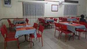 una sala da pranzo con sedie rosse e tavoli in un ristorante di Hotel Premier a Yumbe