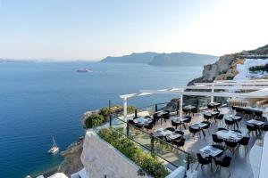 a restaurant on the side of a cliff with the ocean at Santorini Secret Suites & Spa, Small Luxury Hotels of the World in Oia
