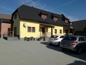 a yellow house with two cars parked in front of it at Apartments Club Telgárt in Telgárt