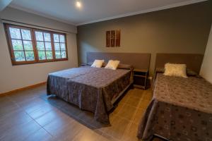 a bedroom with two beds and two windows at Fitz Roy Hostería de Montaña - El Chaltén in El Chalten