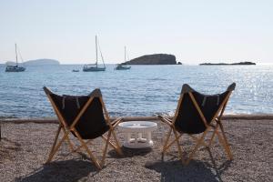 two chairs and a table on the beach with boats at Jacaranda Apartments & Studios in Es Cana