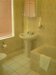 a bathroom with a sink and a tub and a toilet at Holly Trees Hotel in Alsager