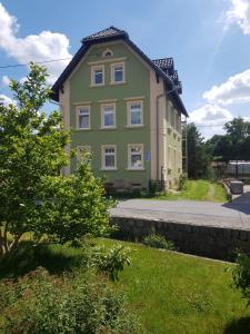 ein grünes Haus mit einem Baum davor in der Unterkunft Ferienwohnung Karlguth in Neustadt in Sachsen