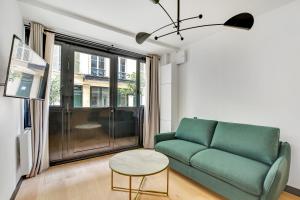 un soggiorno con divano verde e tavolo di Pick A Flat's Apartment in Opera - Rue Grange Batelière a Parigi