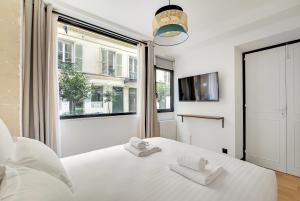 1 dormitorio con cama blanca y ventana en Pick A Flat's Apartment in Opera - Rue Grange Batelière, en París