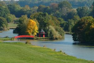 un lac avec un pont rouge et un kiosque dans l'établissement Gîte Design, à Arceau