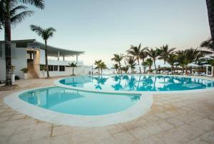 a large swimming pool with palm trees and a building at Private Apartment in Caribe Dominicus 3 SOLO ADULTOS in La Laguna