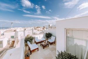 a balcony with white chairs and a view of the city at Dimora Anderì in Polignano a Mare