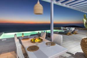 a white table with a bowl of fruit on a patio at Villa Semeli Syros by Divine Property SA in Ano Syros