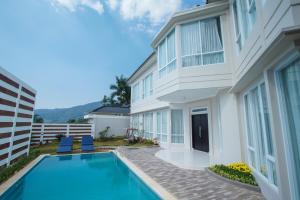 a house with a swimming pool next to a building at Nirvana Villas Puncak in Puncak